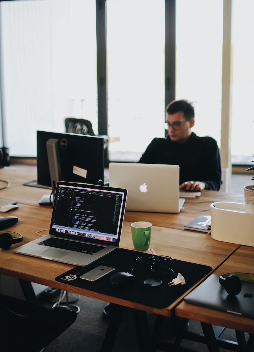 man in black shirt sits behind desk with computers