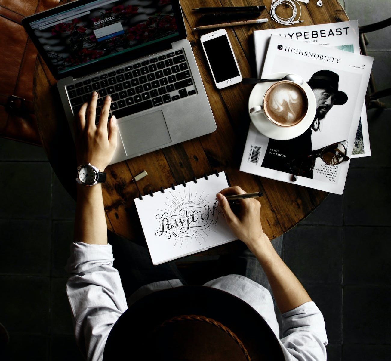 person sitting facing laptop computer with sketch pad